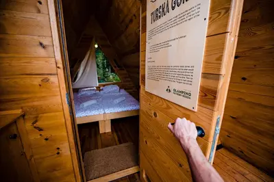 a man is opening the door of a tree house at Glamping FOREST EDGE in Kamnik
