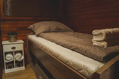 a bed in a wooden room with a night stand at Lucky home in Čatež ob Savi