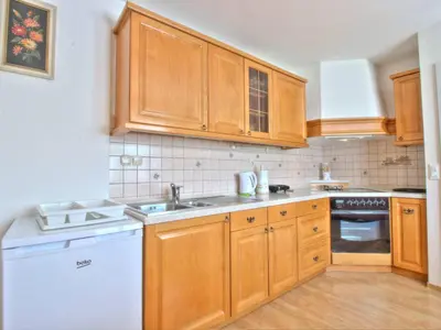 a kitchen with wooden cabinets and a white dishwasher at Apartments Julijana in Bled