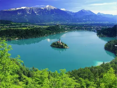an island in the middle of a lake with mountains at Apartments Julijana in Bled