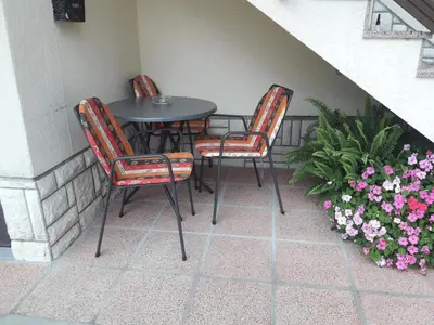 three chairs and a table on a patio with flowers at D-D in Bovec