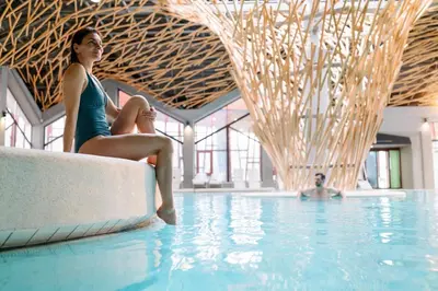 a woman sitting on a couch in a swimming pool at Terme Olimia - Aparthotel Rosa in Podčetrtek