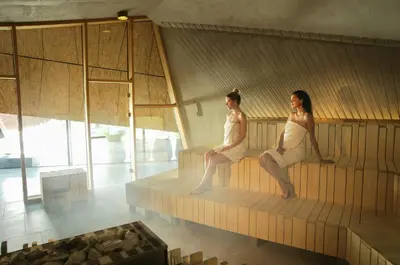 two women in white bathing suits sitting on a bench at Terme Olimia - Aparthotel Rosa in Podčetrtek