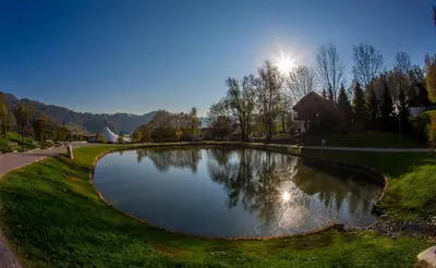 a pond in a park with the sun in the background at Terme Olimia - Aparthotel Rosa in Podčetrtek