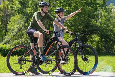 two people riding bikes on a road at Hostel pod Voglom in Bohinj