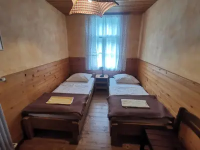 a room with three beds and a window at Hostel pod Voglom in Bohinj