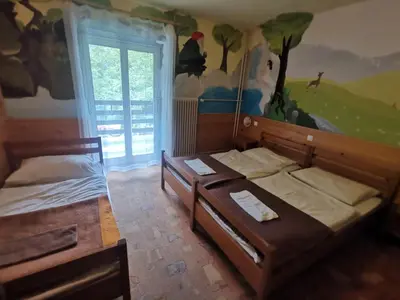 two beds in a room with a mural on the wall at Hostel pod Voglom in Bohinj