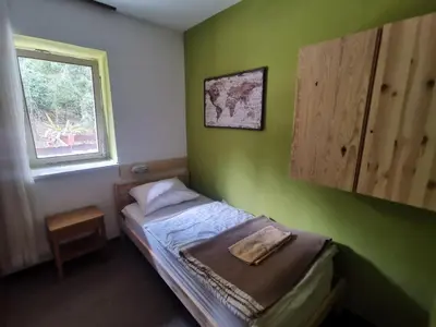 a small bedroom with a bed with a window at Hostel pod Voglom in Bohinj