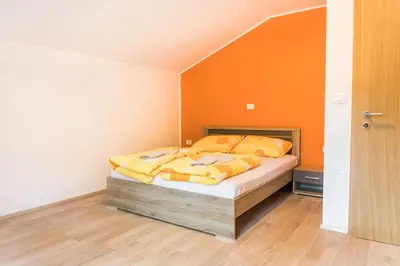 a bedroom with a bed with an orange wall at Guest House Rosi in Tolmin