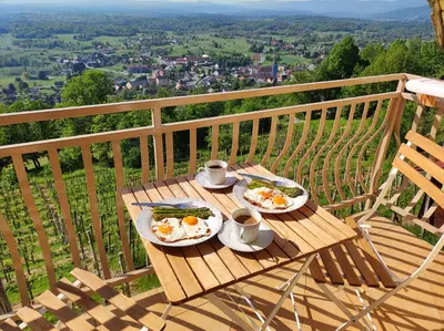 two plates of eggs on a wooden table on a balcony at Zidanica-Vineyard Cottage Jakše in Semič