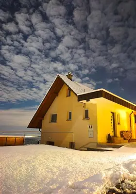a house in the snow with a cloudy sky at Zidanica-Vineyard Cottage Jakše in Semič