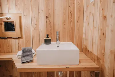 a bathroom with a white sink on a wooden counter at Koča Bistra - Velika planina in Stahovica