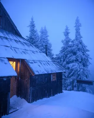a barn covered in snow with trees in the background at Koča Bistra - Velika planina in Stahovica