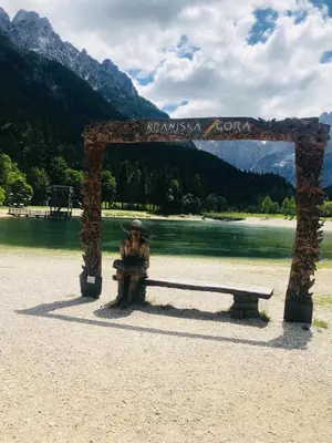 a statue sitting under a bench next to a lake at Apartment Story in Kranjska Gora