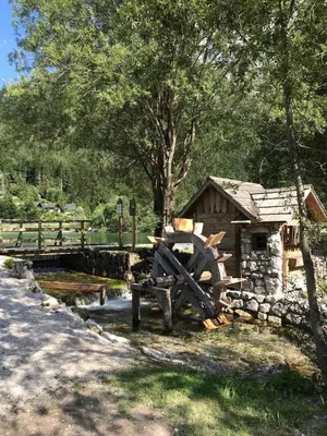 a woodenmill sitting next to a building next to a pond at Apartment Story in Kranjska Gora
