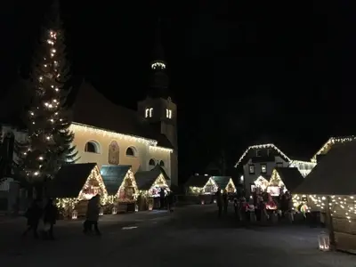 a group of people walking around a christmas village at night at Apartment Story in Kranjska Gora