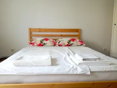a bed with white sheets and pillows with towels on it at Bright Side Studios in Ljubljana
