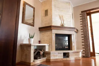 a living room with a stone fireplace and a mirror at Domačija pri Damjanu in Kozina