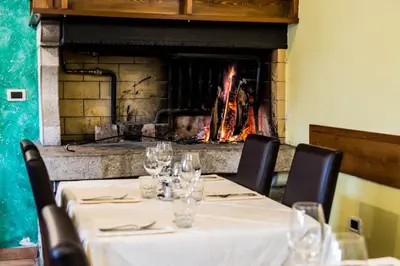 a table with wine glasses and a fireplace at Domačija pri Damjanu in Kozina