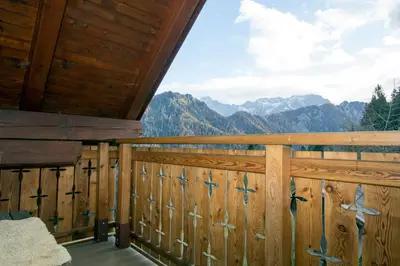 a room with a wooden fence with a view of mountains at Kmetija Matk in Solčava