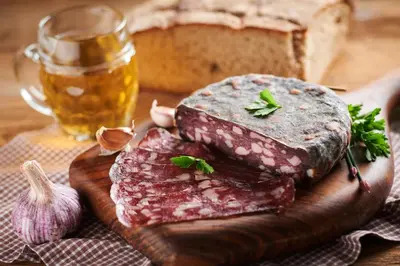 a piece of meat on a cutting board with a loaf of bread at Kmetija Matk in Solčava