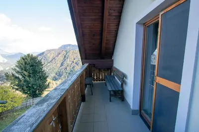 a balcony with a bench and a view of mountains at Kmetija Matk in Solčava