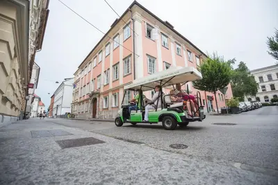 a group of people riding a golf cart down a street at Feel Ljubljana Centre in Ljubljana