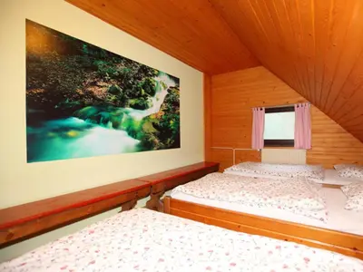 two beds in a room with a painting on the wall at PLANINSKA KOČA NA GOZDU in Kranjska Gora