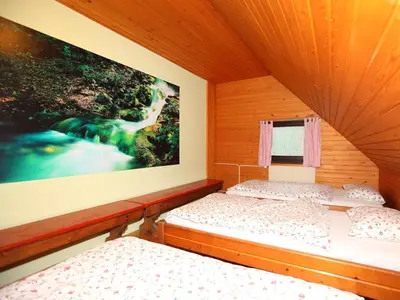 two beds in a room with a picture on the wall at PLANINSKA KOČA NA GOZDU in Kranjska Gora