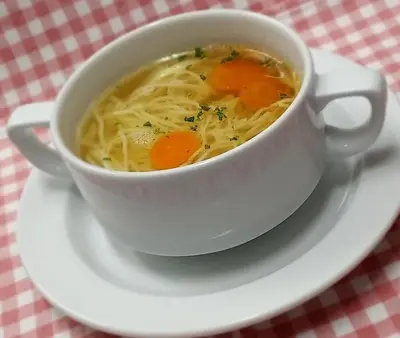 a cup of soup on a plate on a table at PLANINSKA KOČA NA GOZDU in Kranjska Gora