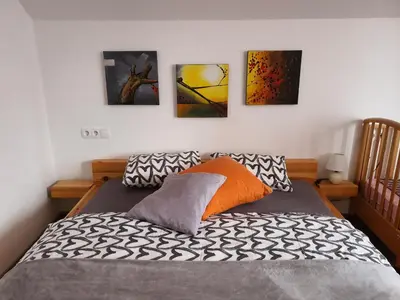 a bedroom with a bed with four paintings on the wall at Apartmaji Daniel in Kranjska Gora