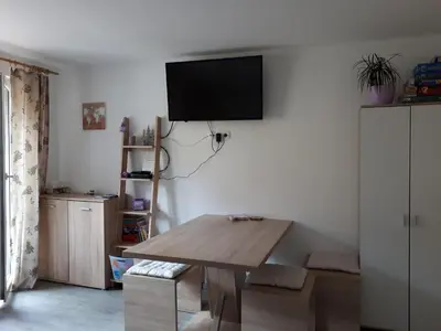 a living room with a table and a tv on the wall at Apartmaji Daniel in Kranjska Gora