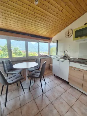 a kitchen with a table and chairs and some windows at Apartment Bruna Vučič in Bovec