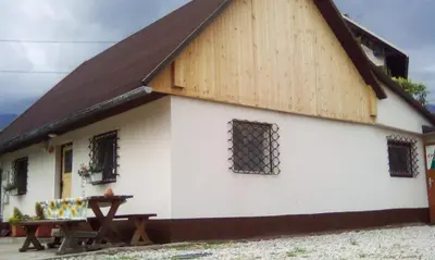 a large white building with a wooden roof and a picnic table at Apartma Pr' Vok in Lesce