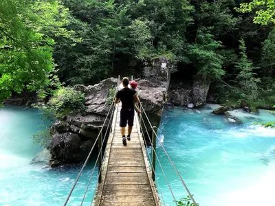 a man walking across a suspension bridge over a river at Apartma Center in Bovec