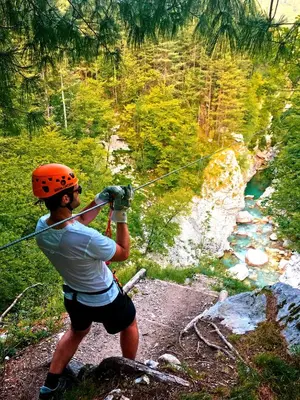 a man in an orange helmet is holding onto a rope at Apartma Center in Bovec