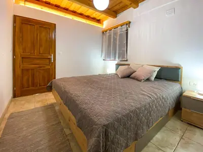 a bedroom with a bed and a wooden door at Apartment Feher Lendava in Lendava