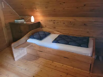 a bed in a room with a wooden wall at Počitniška hiša Radovna in Zgornja Radovna