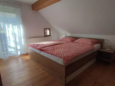 a bedroom with a bed with a red comforter at Apartmaji Mojca in Bohinj