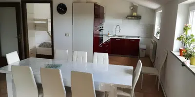 a kitchen with a dining table and white chairs at Apartma Čeh in Gabrovica pri Črnem Kalu