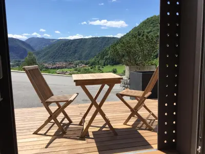 two chairs and a table on a deck with mountains at Apartmaji 43 in Tolmin