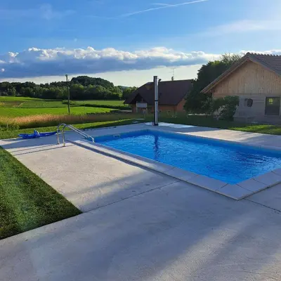 a swimming pool in a yard next to a house at Apartments Bukor with seasonal pool in Lukovica pri Domžalah
