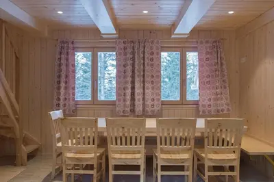 a dining room with a table and chairs and windows at Koča Predilnica Velika Planina in Kamniška Bistrica