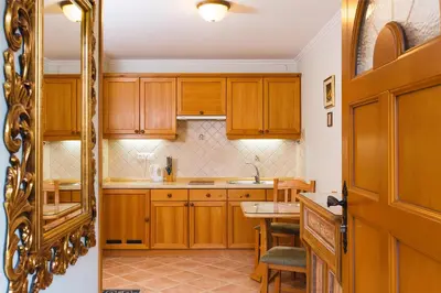 a kitchen with wooden cabinets and a table and a mirror at Apartments Dolar in Bled