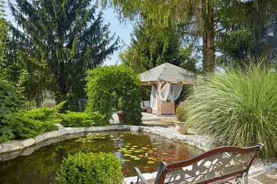 a garden with a pond with a bench and a koi at Karavla Private Villa in Šentilj