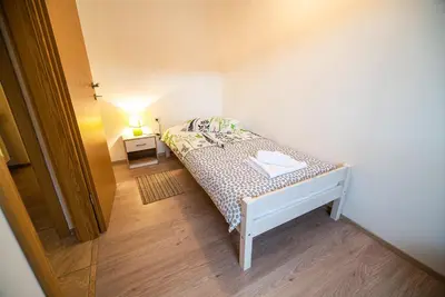 a small bedroom with a bed and a table with a lamp at Apartments Ole in Tolmin