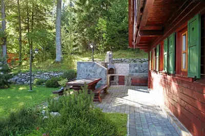 a patio with a wooden bench next to a house at Natural Wooden Sweetheart in Padeški Vrh