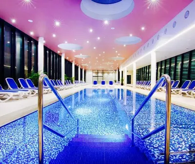 a large swimming pool with blue chairs and a purple ceiling at Apartment Maja Moravske Toplice in Moravske Toplice