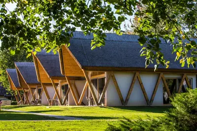 a building with a gambrel roof on a grass field at Hotel Ajda Depandance Prekmurska Vas - Terme 3000 - Sava Hotels & Resorts in Moravske Toplice