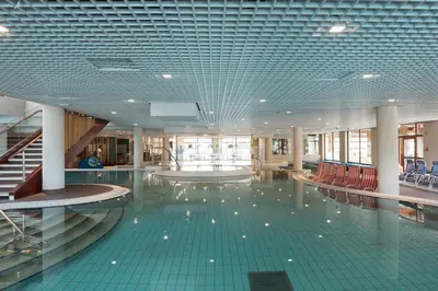 a large swimming pool with red chairs in a building at Hotel Ajda Depandance Prekmurska Vas - Terme 3000 - Sava Hotels & Resorts in Moravske Toplice